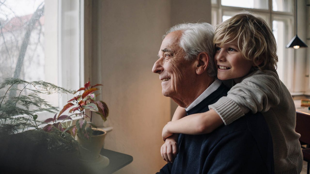 Happy grandson embracing grandfather at home