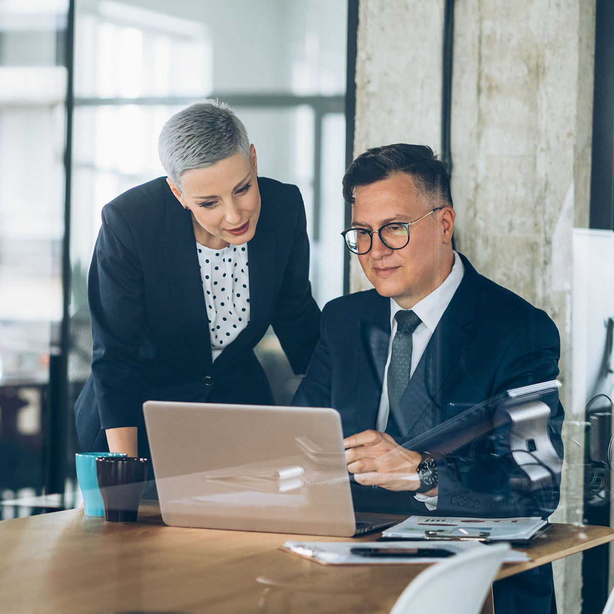 Businessman and business woman working together at the office using laptop and documents