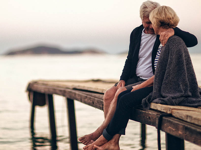 Older couple cuddling on wharf