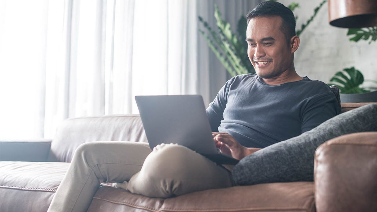 Man on lounge with laptop in casual home setting
