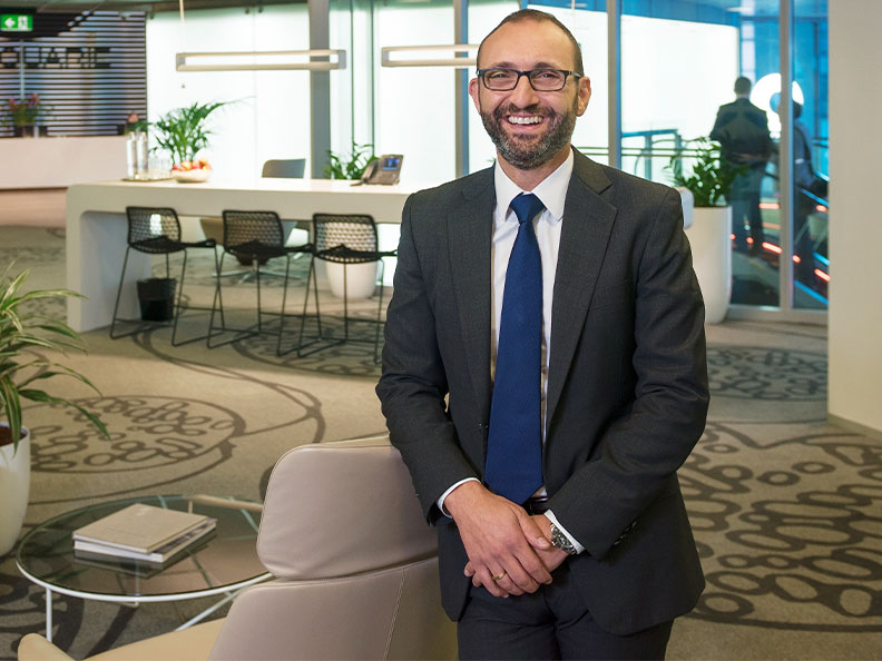 Professional man in a suit smiling in the lobby of a Macquarie office.