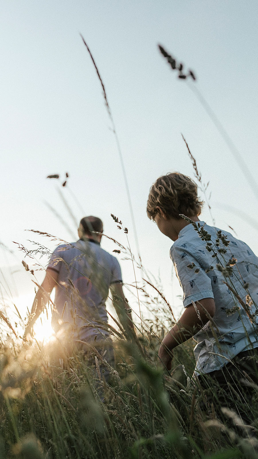 father and boy in field of grass