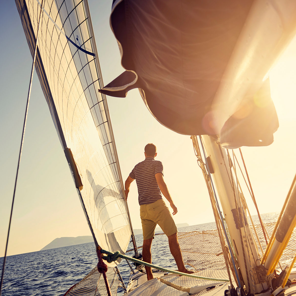 man standing on sail boat looking at horizon
