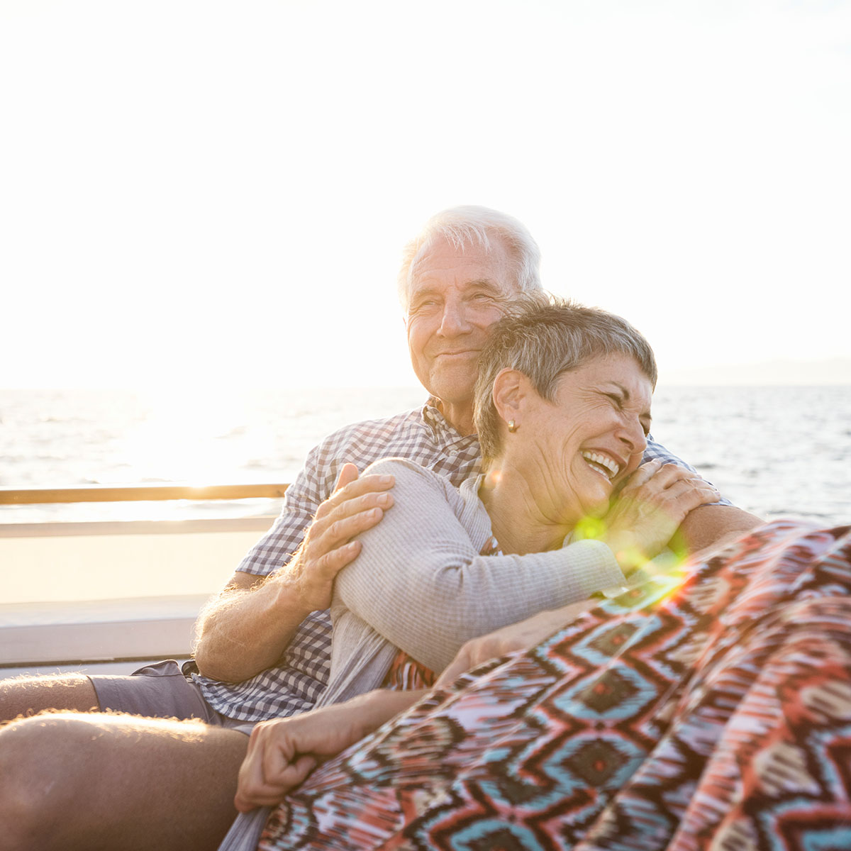 middle aged couple hugging and laughing on boat