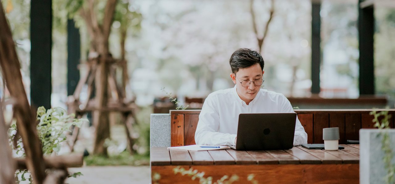 Asian man working on laptop outdoors