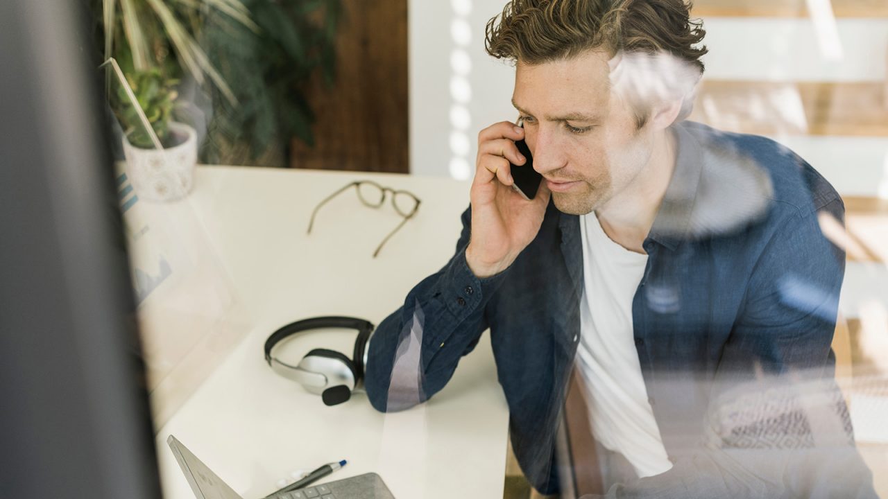 Man talking on mobile phone whilst on laptop
