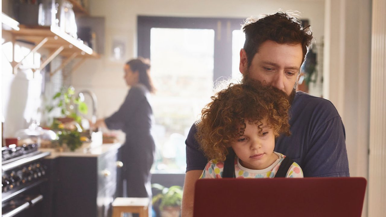 Father and daughter looking at laptop in kitchen
