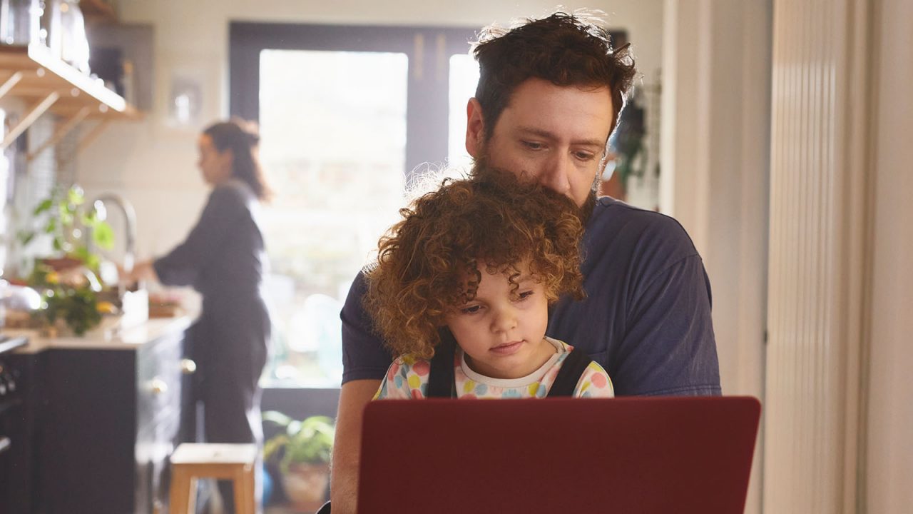 Father and daughter looking at laptop in kitchen